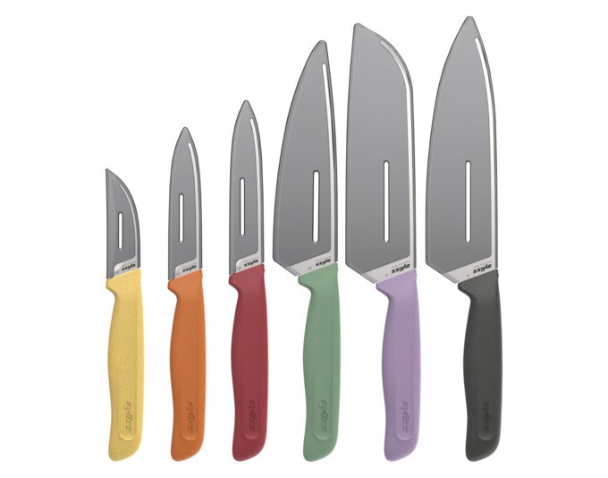 Sechs ZYLISS Küchenmesser mit Edelstahlklingen und farbigen Griffen aus Weizenstrohmaterial, liegend nebeneinander auf heller Fläche.