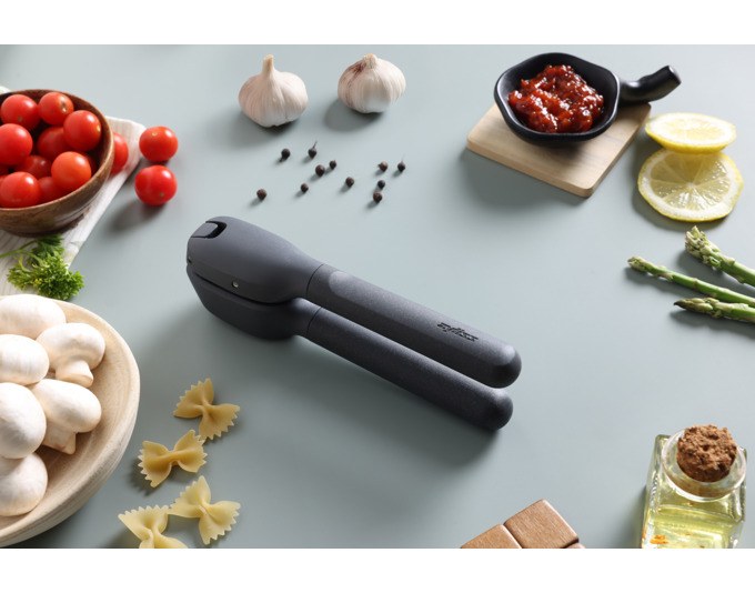 Schwarze ZYLISS Knoblauchpresse Classic aus Kunststoff mit Griffen, Presskammer und Schwenkgitter, freigestellt auf weissem Hintergrund abgebildet.