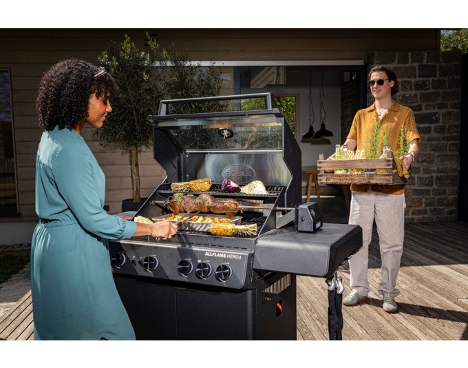 Silberner und schwarzer RÖSLE Drehspiess Allflame aus Edelstahl mit 6-Kant-Form und vier Halterungen für Grillgut, montiert an einem Grill.