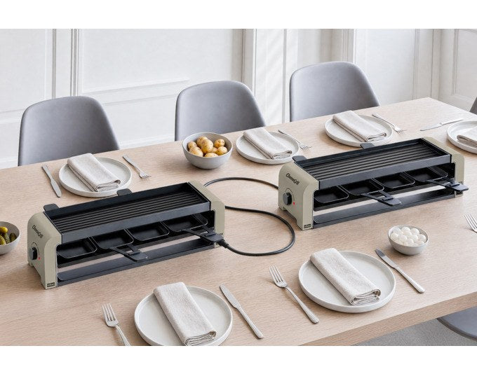 Zwei STÖCKLI CheeseGrill 4 Connect Tischgrills in Ivory Gold mit acht Pfännchen, Kunststoffspachteln und einer Wende-Grillplatte aus Aluguss.