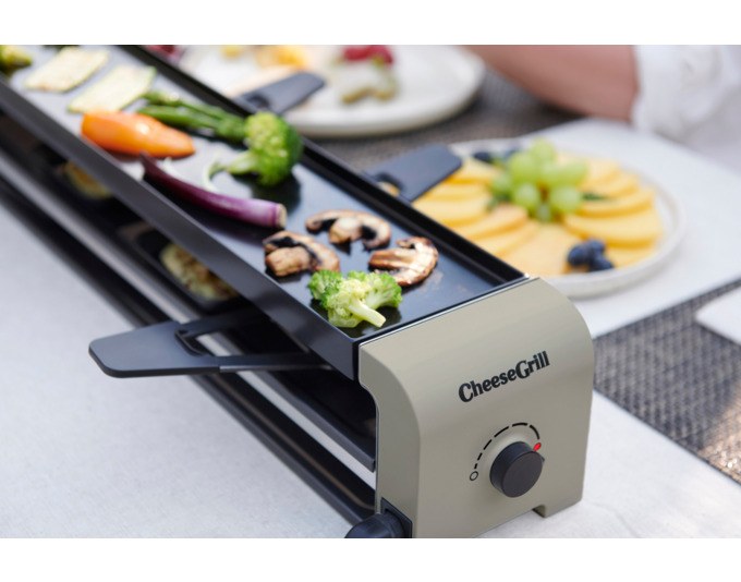 Zwei STÖCKLI CheeseGrill 4 Connect Tischgrills in Ivory Gold mit acht Pfännchen, Kunststoffspachteln und einer Wende-Grillplatte aus Aluguss.