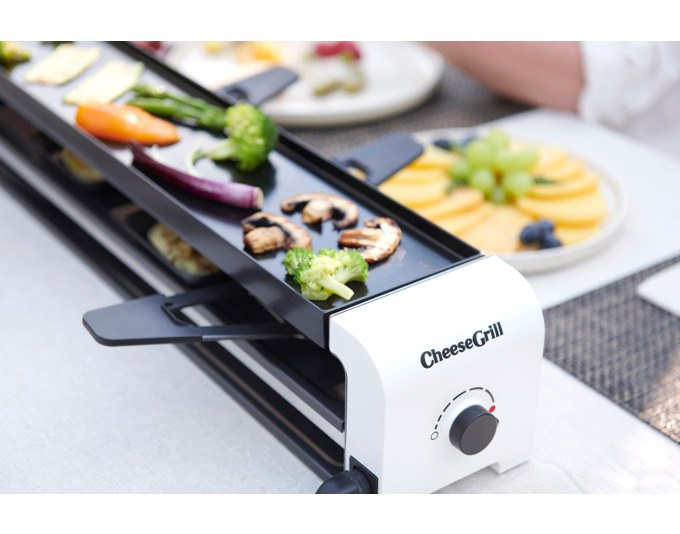 Weisser STÖCKLI Tischgrill CheeseGrill 4 Connect mit wendbarer Grillplatte, vier Pfännchen und Kunststoffspachteln auf hellem Untergrund.