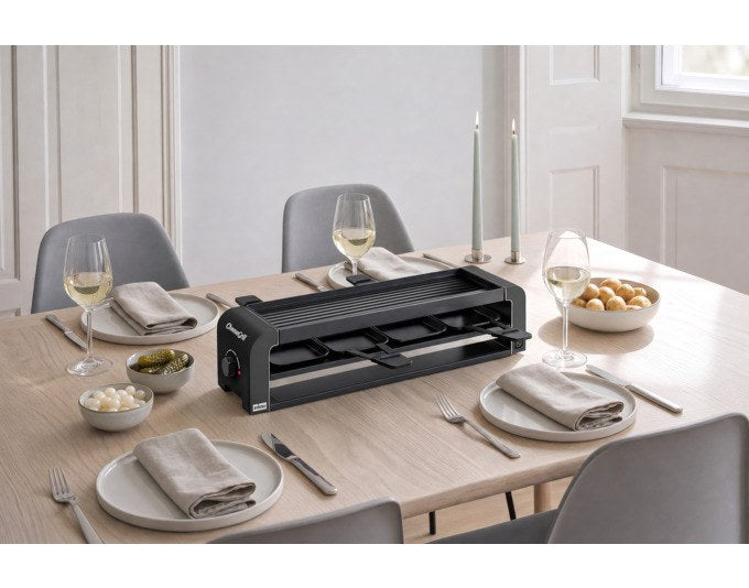 Schwarzer STÖCKLI Tischgrill CheeseGrill 4 Connect mit wendbarer Grillplatte, vier Pfännchen und Kunststoffspachtel auf hellem Untergrund.