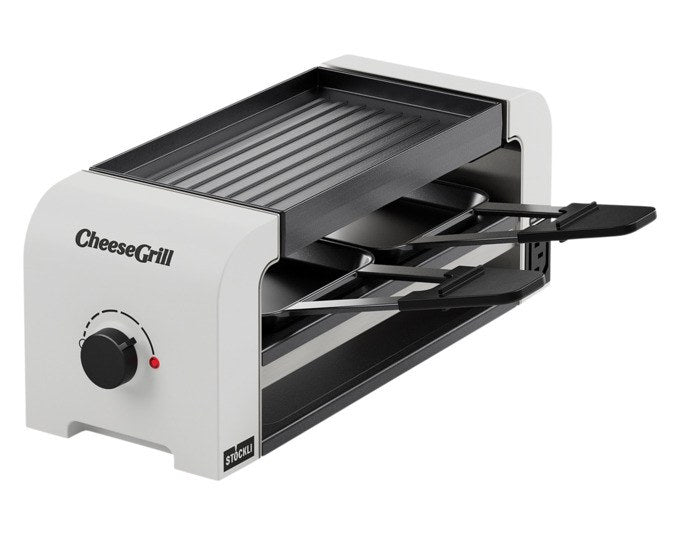 Weisser Tischgrill STÖCKLI CheeseGrill 2 Connect mit wendbarer Aluguss-Grillplatte, zwei Pfännchen und Kunststoffspachtel auf hellem Untergrund.