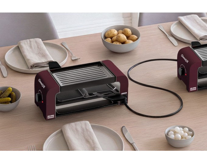 Produktfoto des STÖCKLI CheeseGrill 2 Connect in Merlot Red mit zwei antihaftbeschichteten Pfännchen und wendbarer Aluguss-Grillplatte.