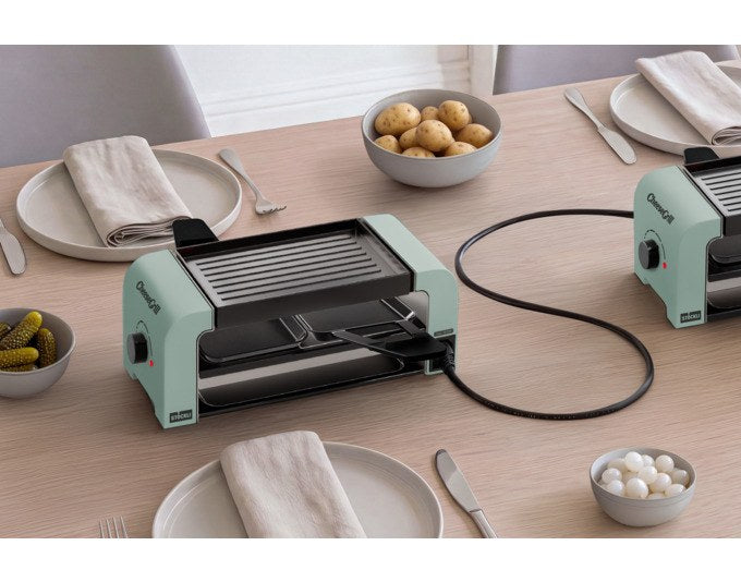 STÖCKLI CheeseGrill 2 Connect in Mint Green mit zwei antihaftbeschichteten Pfännchen, wendbarer Aluguss-Grillplatte und Kunststoffspachteln auf hellem Untergrund