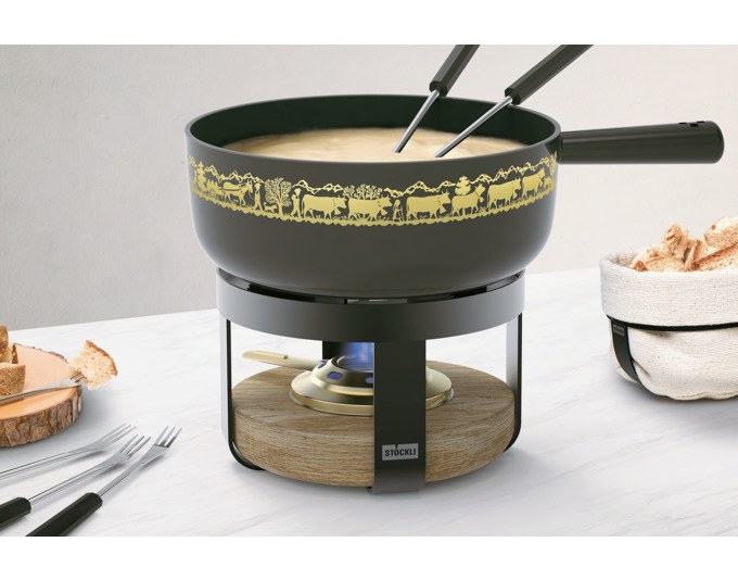 Schwarzes Fondue-Set STÖCKLI Pilatus Wood Classic mit Gusseisen-Caquelon, goldenem Alp-Dekor, Holzeinsatz-Rechaud und sechs Fonduegabeln.