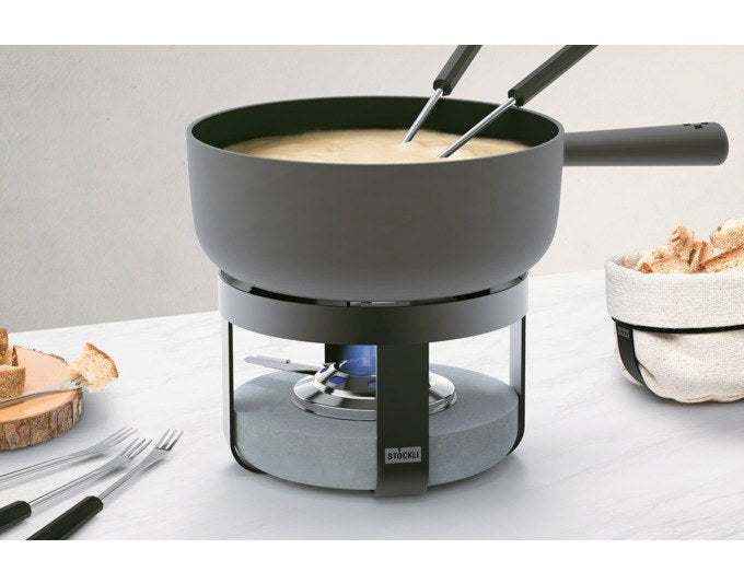 Schwarzes Fondueset STÖCKLI Pilatus Stone Classic 22 mit rundem Caquelon aus Gusseisen, Rechaud mit Betoneinsatz und sechs Käsefonduegabeln.