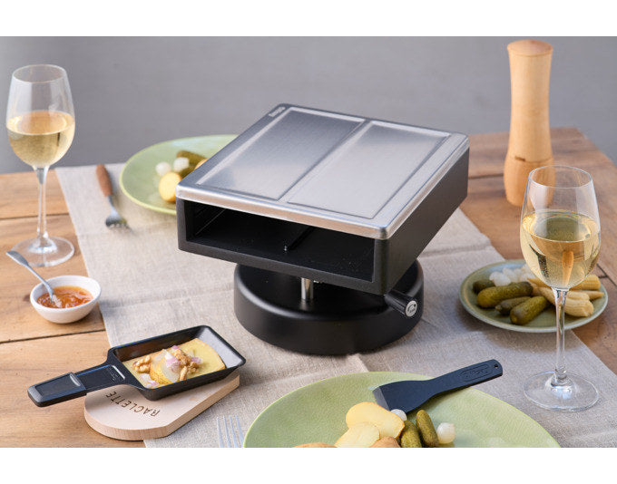 Raclette-Aufsatz SIERRE von KISAG aus Aluminium-Druckguss mit Edelstahldeckel, inklusive vier Pfännchen und Spachteln, Farben Schwarz und Silber.