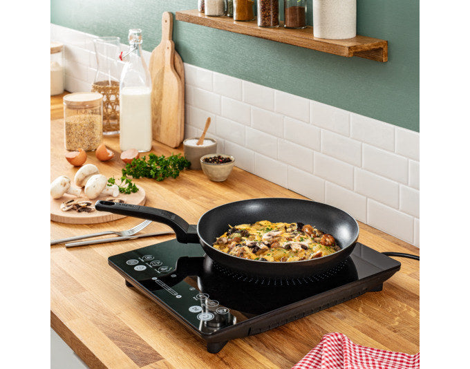 Schwarze TEFAL Induktionsplatte IH2108 mit digitalem Display und Bedienfeld, flache Bauform, auf heller Arbeitsfläche platziert.