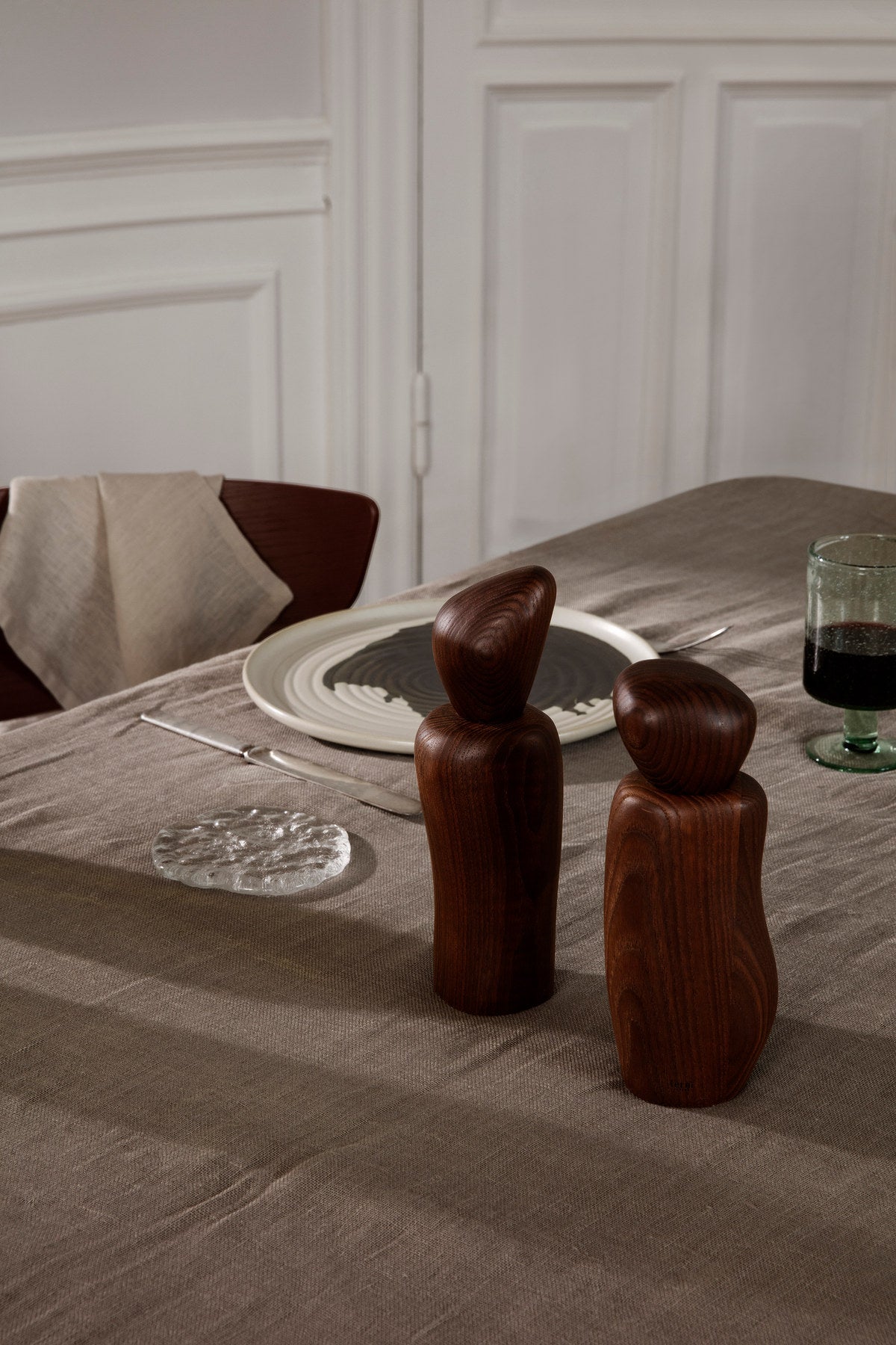 Cairn Mühle von Ferm Living aus dunkelbraunem, karbonisiertem Eschenholz mit organischer, runder Form, stehend auf einer Küchenarbeitsfläche.