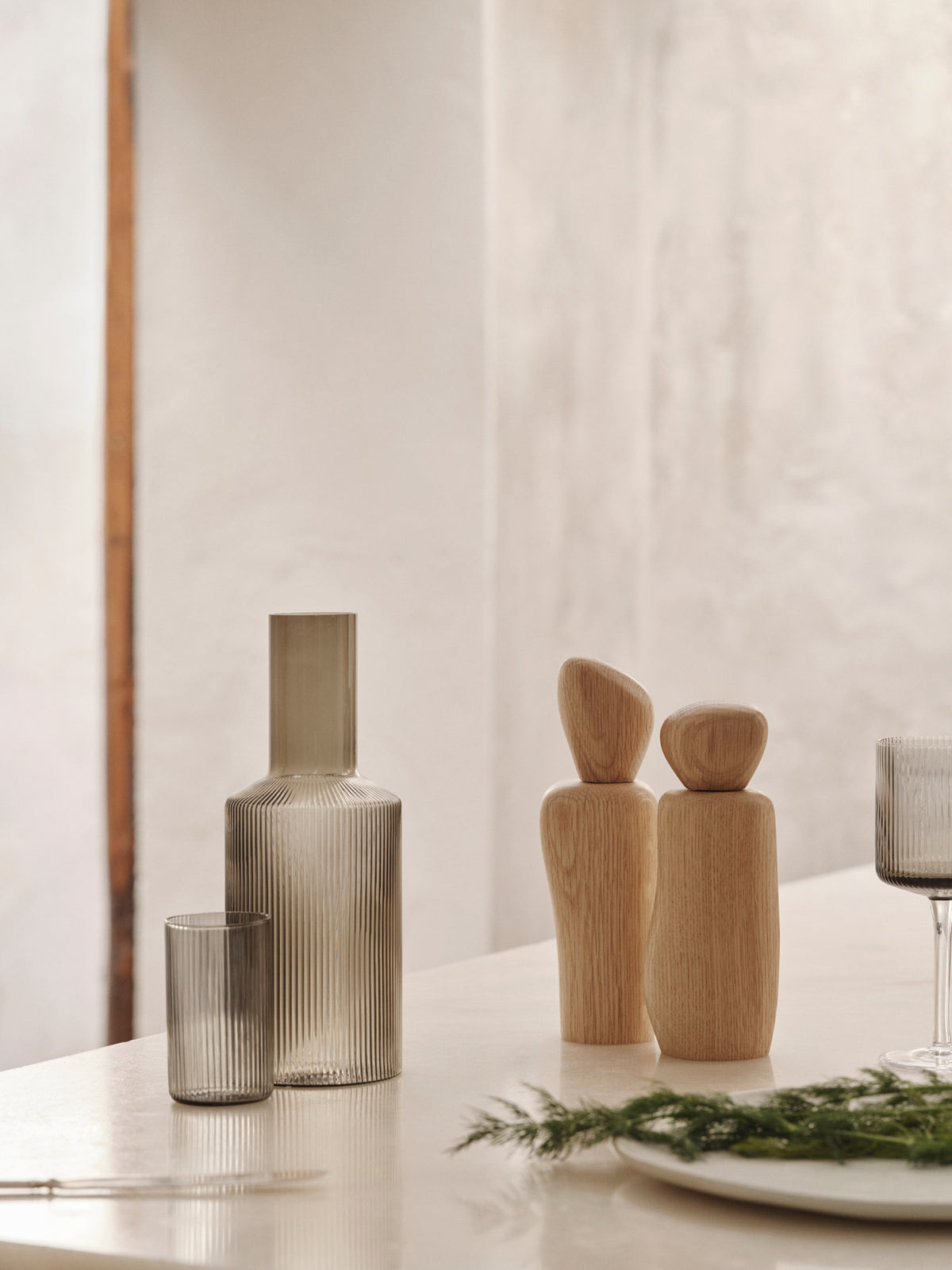 Kiesel-Mühle von Ferm Living in Dunkelbraun, FSC-zertifiziertes Eschenholz mit karbonisierter Oberfläche, kieselähnliche skulpturale Form auf hellem Hintergrund.