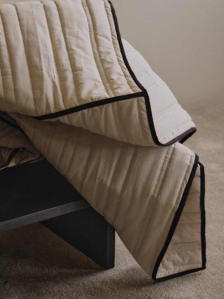 Elegante Vari Quilted Tagesdecke in sanften Natur- und Schokoladentönen, ideal für ein stilvolles Schlafzimmer. Von Ferm Living.