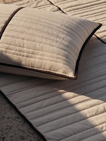 Elegante Tagesdecke mit feinem Steppmuster in warmen Erdtönen, ideal für ein modernes und einladendes Schlafzimmer. Von Ferm Living.
