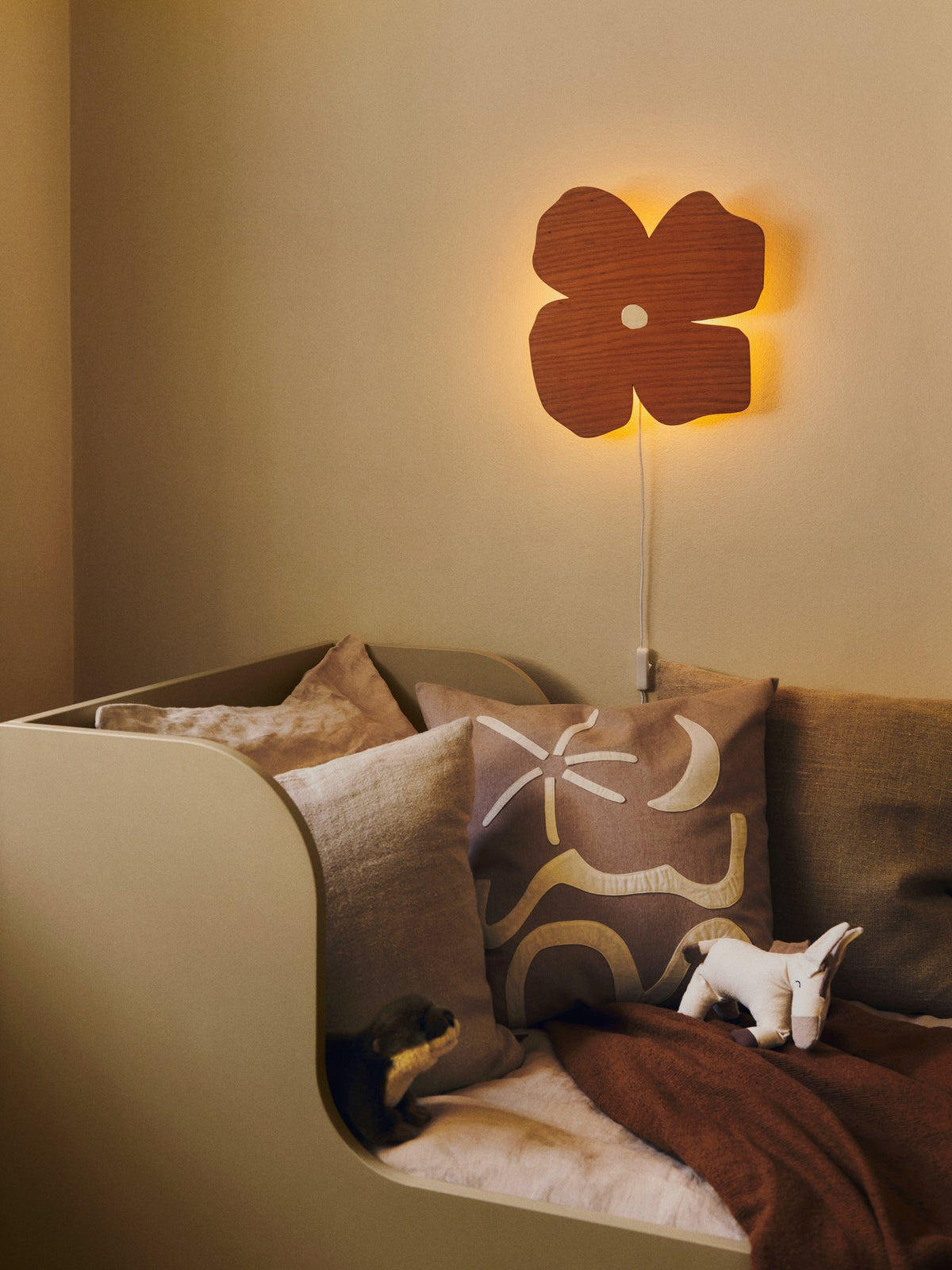 Wandleuchte Poesie von Ferm Living in Brown Clay, blumenförmig aus lackiertem Eichenfurnier, montiert an weisser Wand.