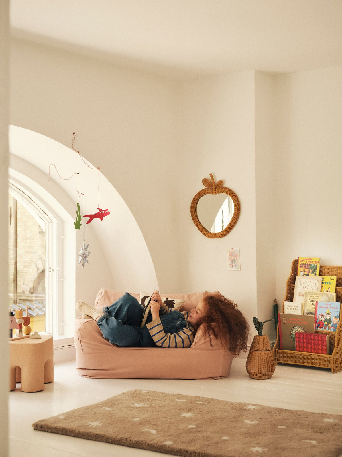 Foto eines Rivan Vitrinen-Bücherregals aus geflochtenem Rattan mit wellenförmigem Rand und nach vorne gerichteten Regalböden, Farbe Natur.