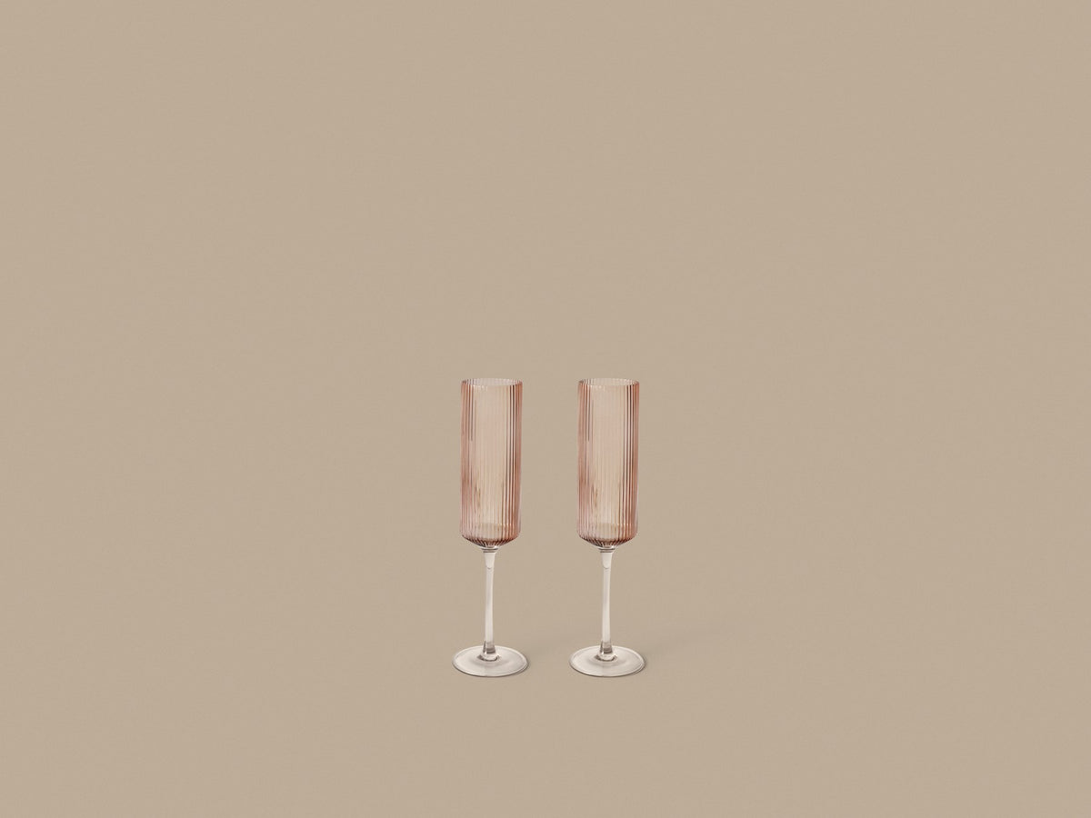 Zwei Ripple Champagnerflöten von Ferm Living aus mundgeblasenem Glas mit geriffelter Oberfläche, Farbe Blush, schlanke geometrische Form.