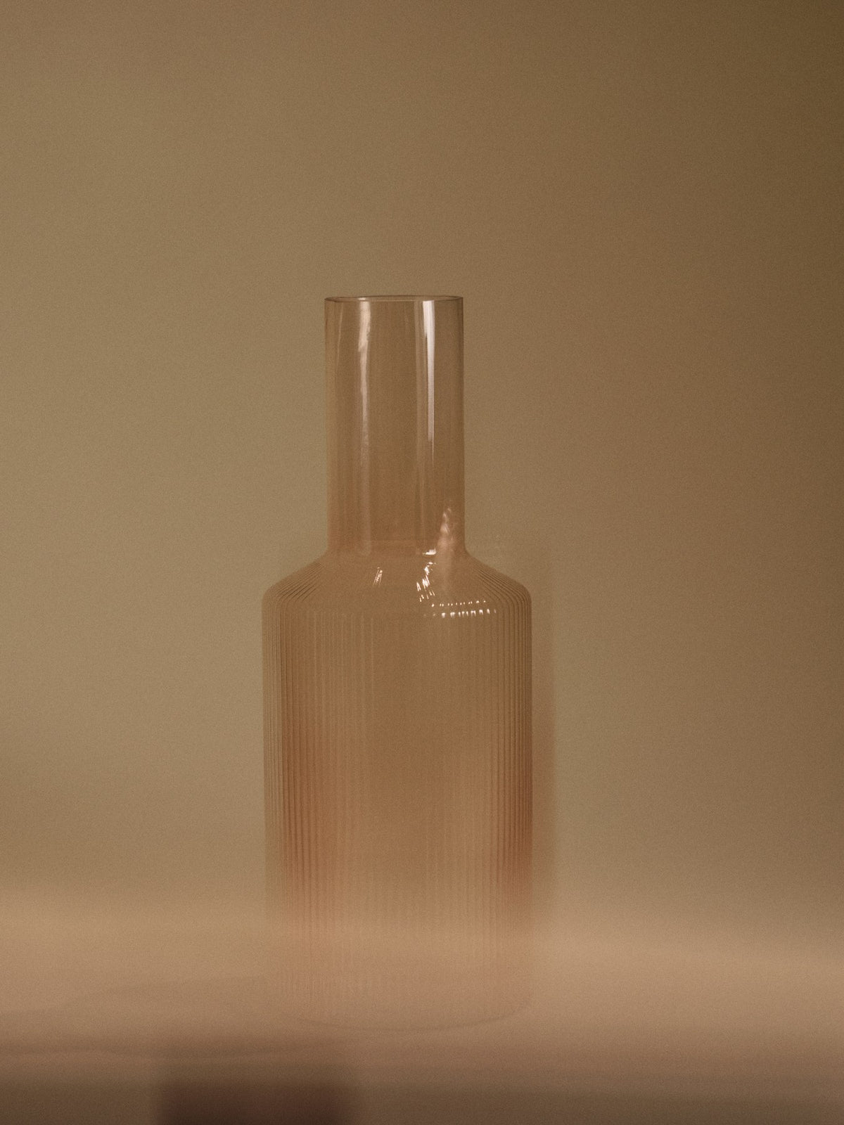Mundgeblasene Glaskaraffe mit geriffelter Oberfläche, geometrischer Form, in Farbe Blush, auf hellem Hintergrund fotografiert.