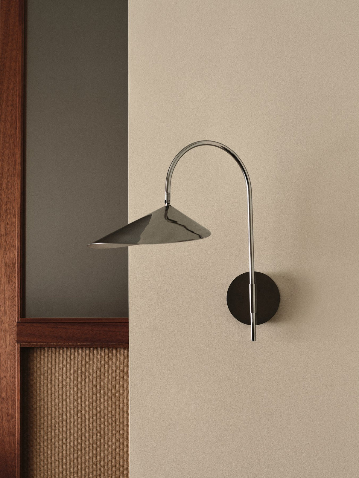 Arum Swivel Wandleuchte von Ferm Living in Edelstahl mit organisch geformtem Lampenschirm, Innenseite matt Off-White, an der Wand montiert.
