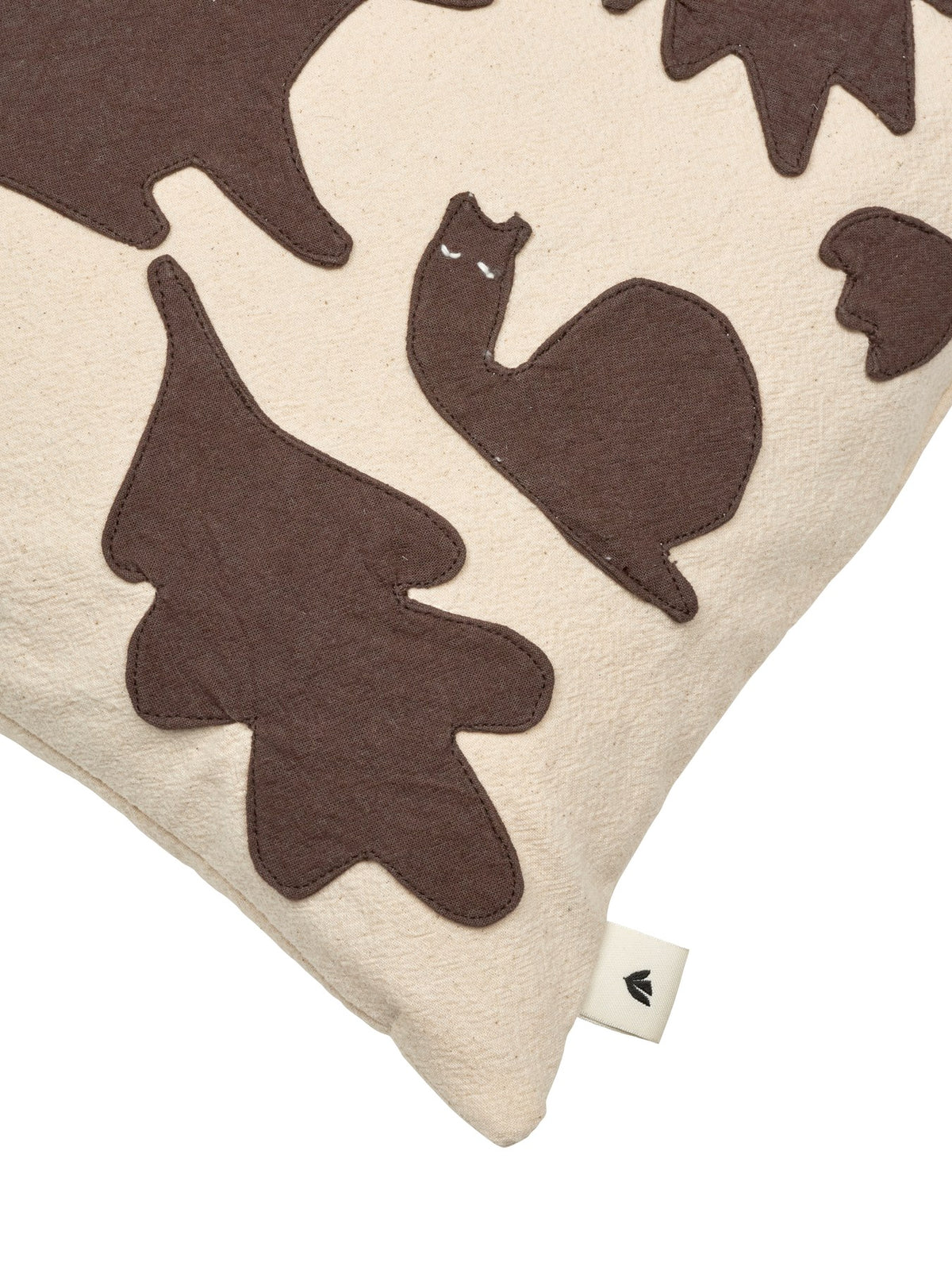 Quadratisches Kissen mit handgestickten Wildtier- und Waldfiguren, Bezug aus Bio-Baumwolle, Farbe Off-White mit Dunkelschokolade-Applikationen.