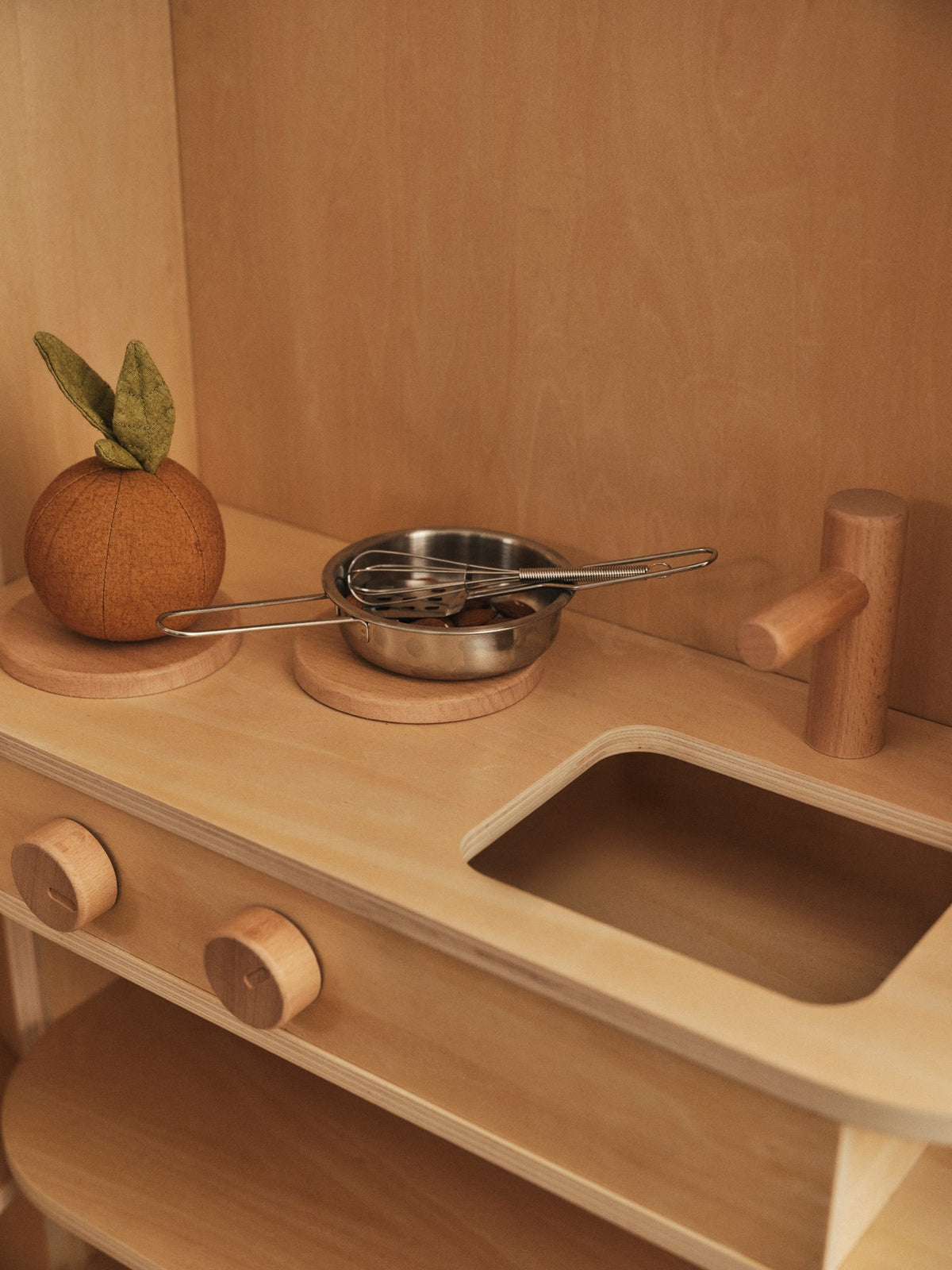 Kinderspielküche Toro von Ferm Living aus Natur-Sperrholz mit Buchendetails, Schiebetür, Wasserhahn und klappbarem Aufbau.