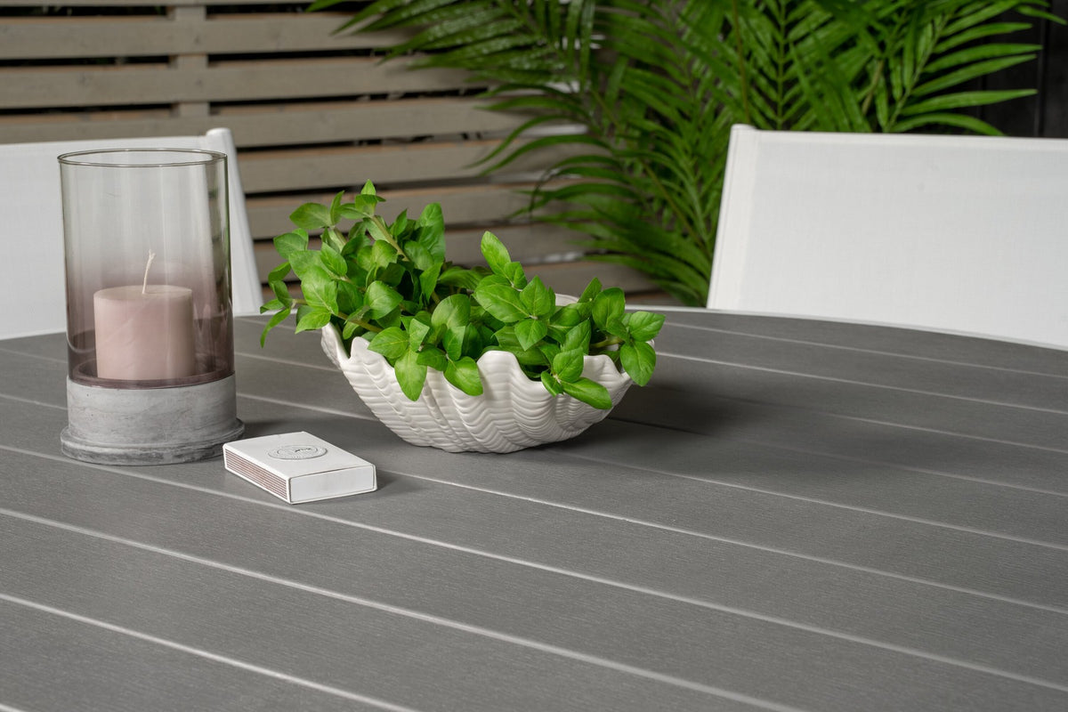 Runder Gartentisch mit grauer Aintwood-Tischplatte und Aluminiumbeinen, umgeben von vier weissen Stühlen Santorini mit pulverbeschichteter Oberfläche.