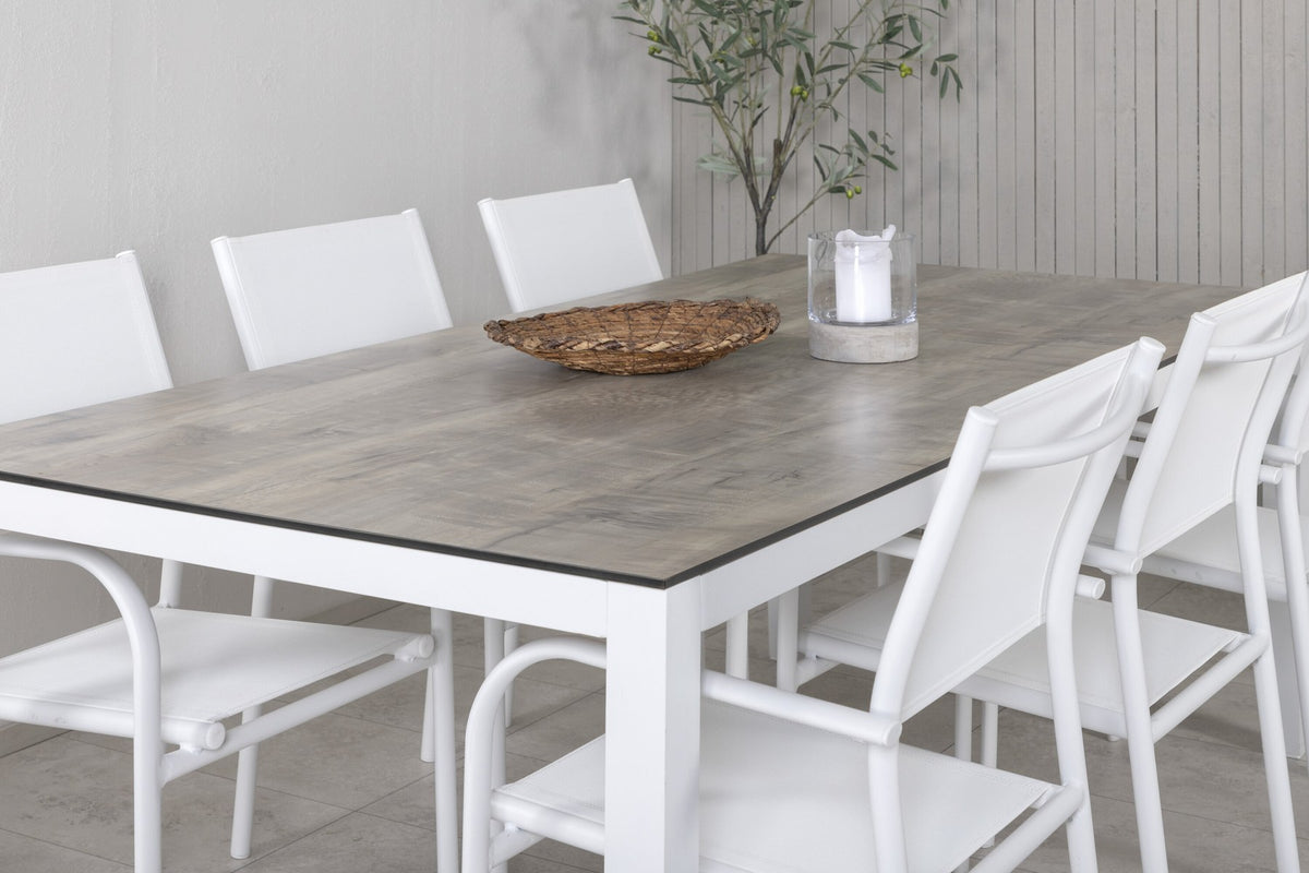 Zwei weisse Aluminium-Stühle mit Pulverbeschichtung und ein rechteckiger Esstisch mit grauer HPL-Tischplatte der Serie Santorini & Llama.