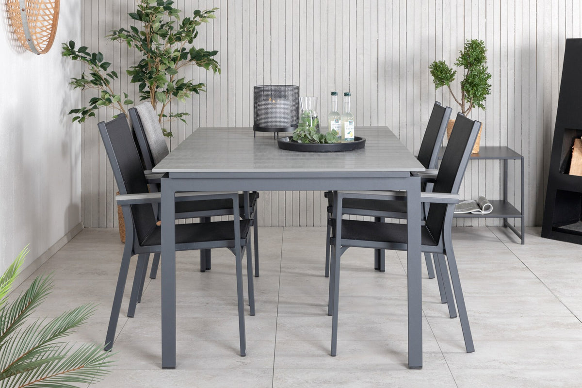 Rechteckiger Esstisch aus Aintwood mit Aluminiumgestell in Anthrazit, dazu zwei stapelbare Stühle mit pulverbeschichteter Oberfläche.