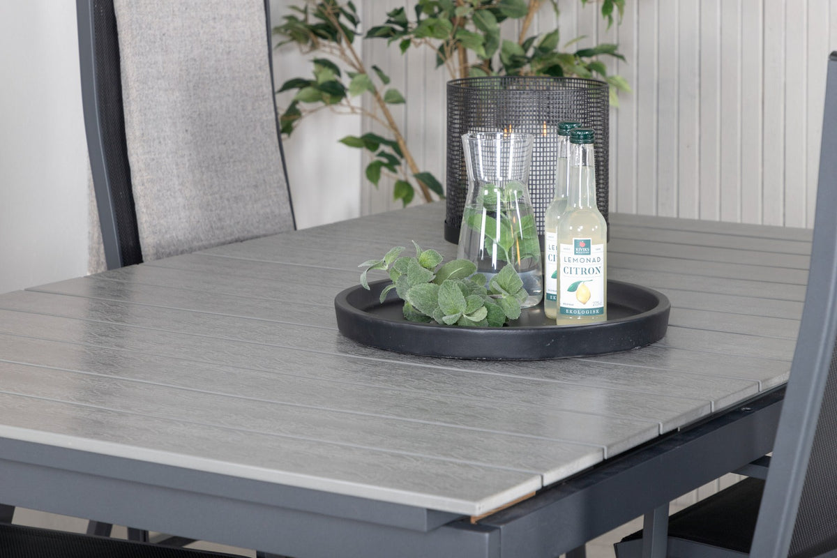 Schwarzer ausziehbarer Gartentisch Levels mit grauer Aintwood-Tischplatte und zwei stapelbaren Copacabana Sesseln aus Aluminium und Aintwood.