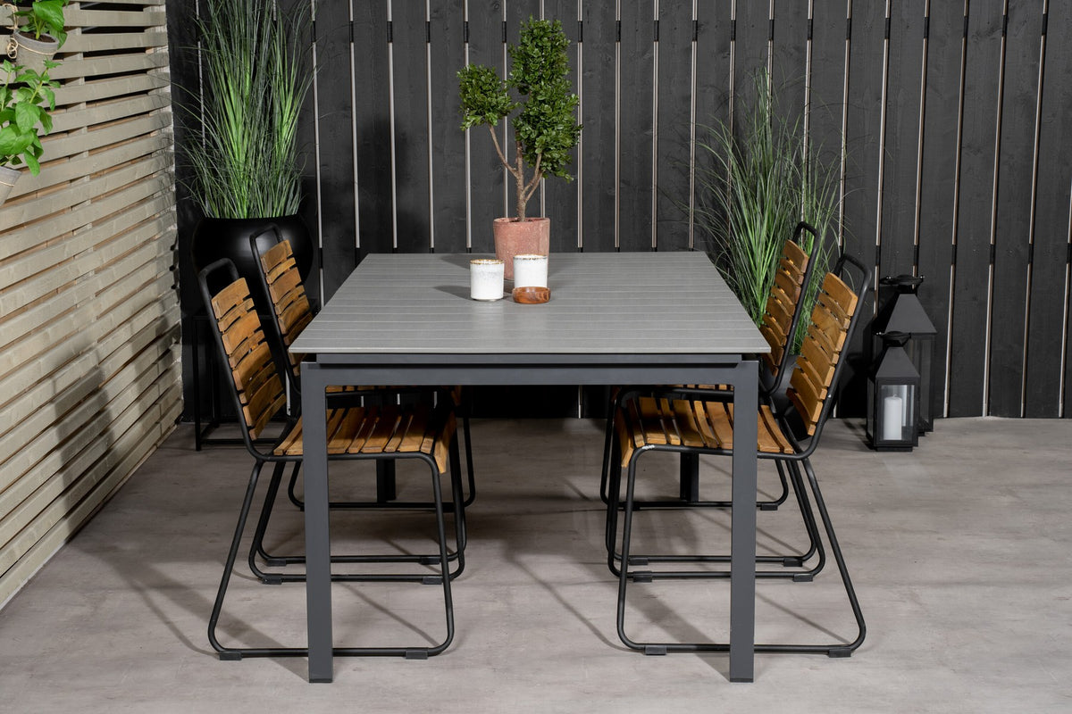 Rechteckiger Gartentisch mit grauer Aintwood-Tischplatte und schwarzem Stahlgestell, daneben zwei Esszimmerstühle aus Aintwood und Aluminium in Natur.