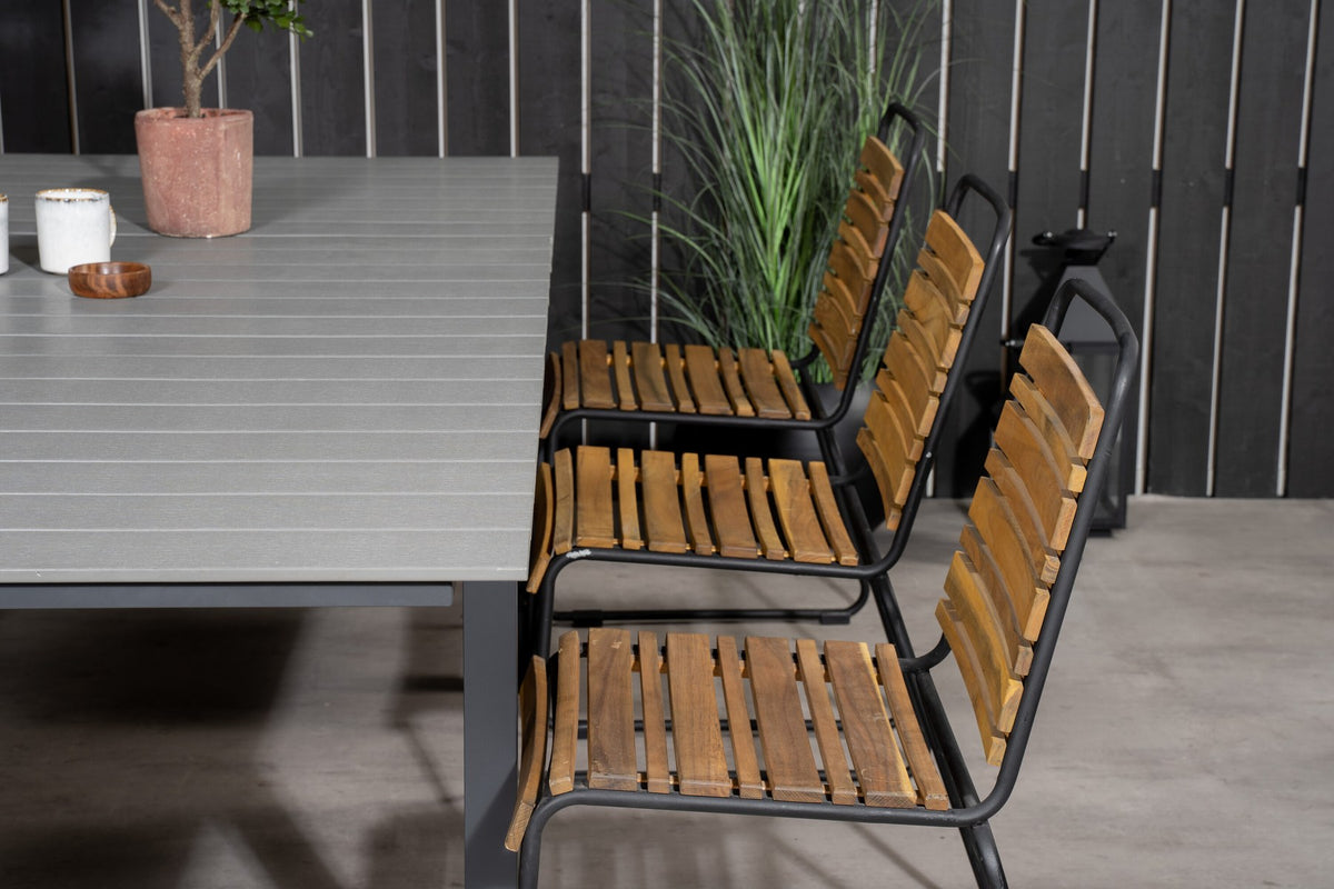 Rechteckiger Gartentisch mit grauer Aintwood-Tischplatte und schwarzem Stahlgestell, daneben zwei Esszimmerstühle aus Aintwood und Aluminium in Natur.