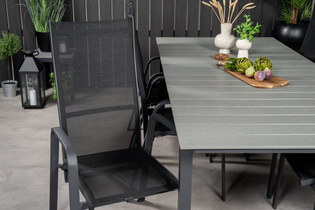 Rechteckiger Gartentisch mit grauer Aintwood-Platte und Aluminiumgestell, daneben zwei stapelbare Copacabana-Relaxsessel in Schwarz.