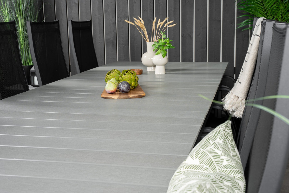 Rechteckiger Gartentisch mit grauer Aintwood-Platte und Aluminiumgestell, daneben zwei stapelbare Copacabana-Relaxsessel in Schwarz.