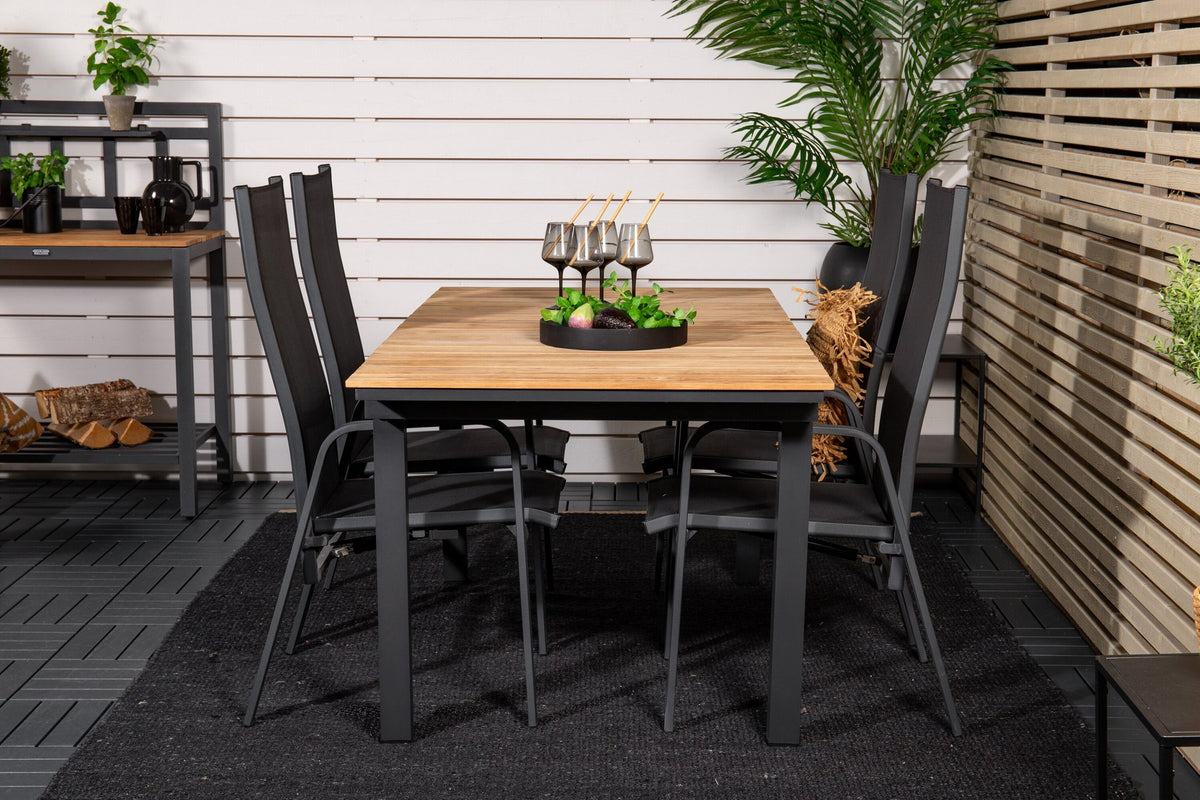Zwei schwarze Relaxsessel Copacabana aus Aluminium mit Pulverbeschichtung neben rechteckigem Teak-Esstisch Mexico in Natur, Gartenmöbel-Set.
