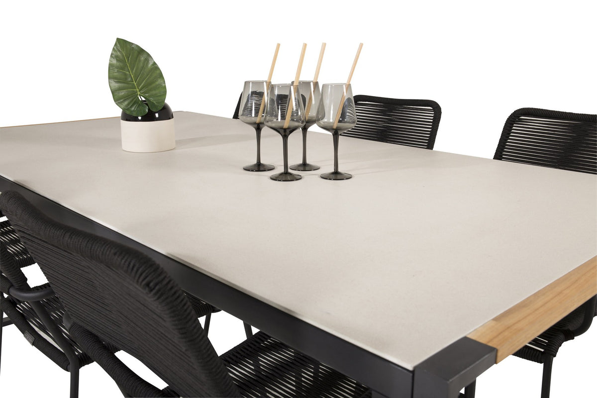 Zwei schwarze Esszimmerstühle mit geflochtener Seilsitzfläche und Aluminiumgestell neben rechteckigem Esstisch mit Glas-Teak-Platte und Stahlbeinen.