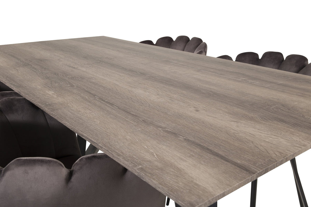 Foto zeigt graue Esszimmerstühle mit Stahlgestell und schwarzem Rahmen um einen rechteckigen MDF-Esstisch in Naturholzoptik, 180x90 cm.