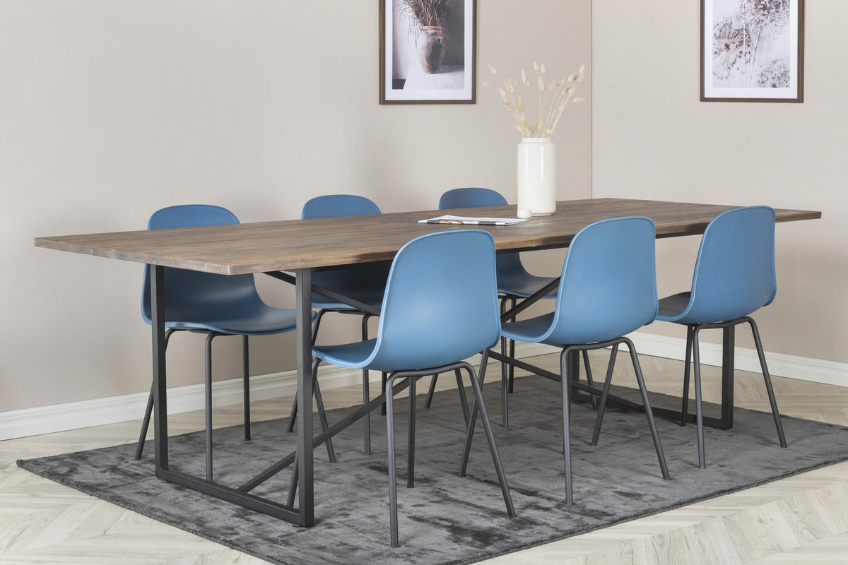 Esstisch Padang mit Teak-Tischplatte in Natur und Stahlbeinen, kombiniert mit blauen Arctic Stühlen mit schwarz pulverbeschichtetem Gestell.