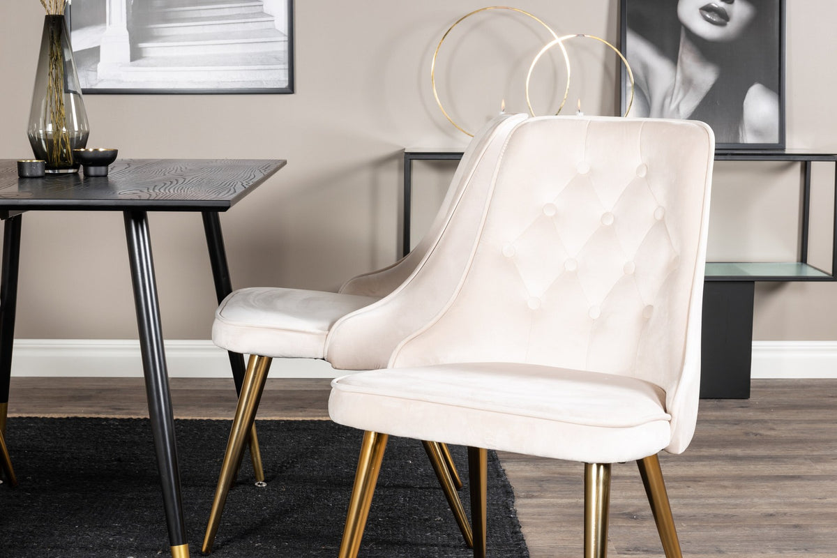 Rechteckiger Esstisch mit schwarzer MDF-Tischplatte und Stahlbeinen, daneben zwei gepolsterte Stühle in Beige mit Messing-Gestell.