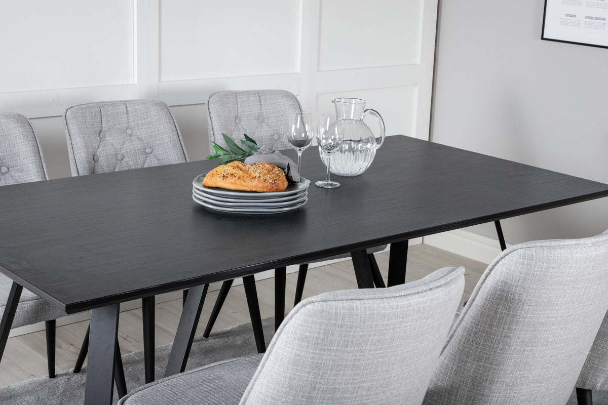 Esszimmerset von Venture Home: rechteckiger Esstisch mit schwarzer MDF-Platte und Stahlgestell, zwei graue Samt-Stühle mit gepolstertem Sitz.
