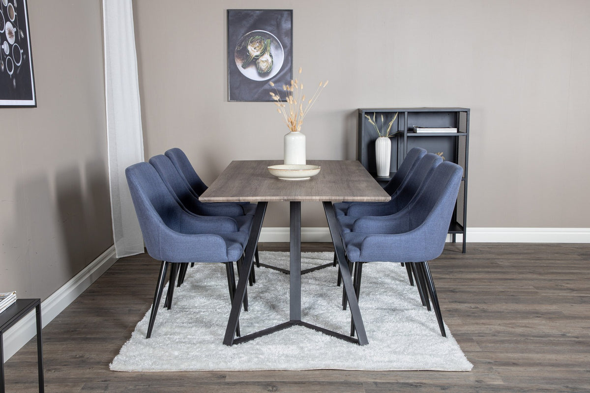 Zwei blaue Esszimmerstühle mit Stahlgestell und schwarz pulverbeschichteter Oberfläche neben einem rechteckigen MDF-Esstisch mit Stahlbeinen.