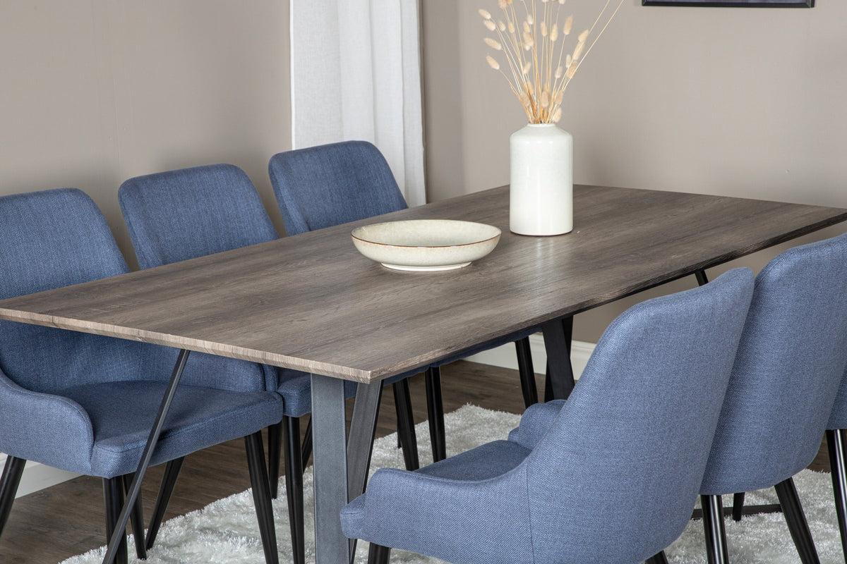 Zwei blaue Esszimmerstühle mit Stahlgestell und schwarz pulverbeschichteter Oberfläche neben einem rechteckigen MDF-Esstisch mit Stahlbeinen.