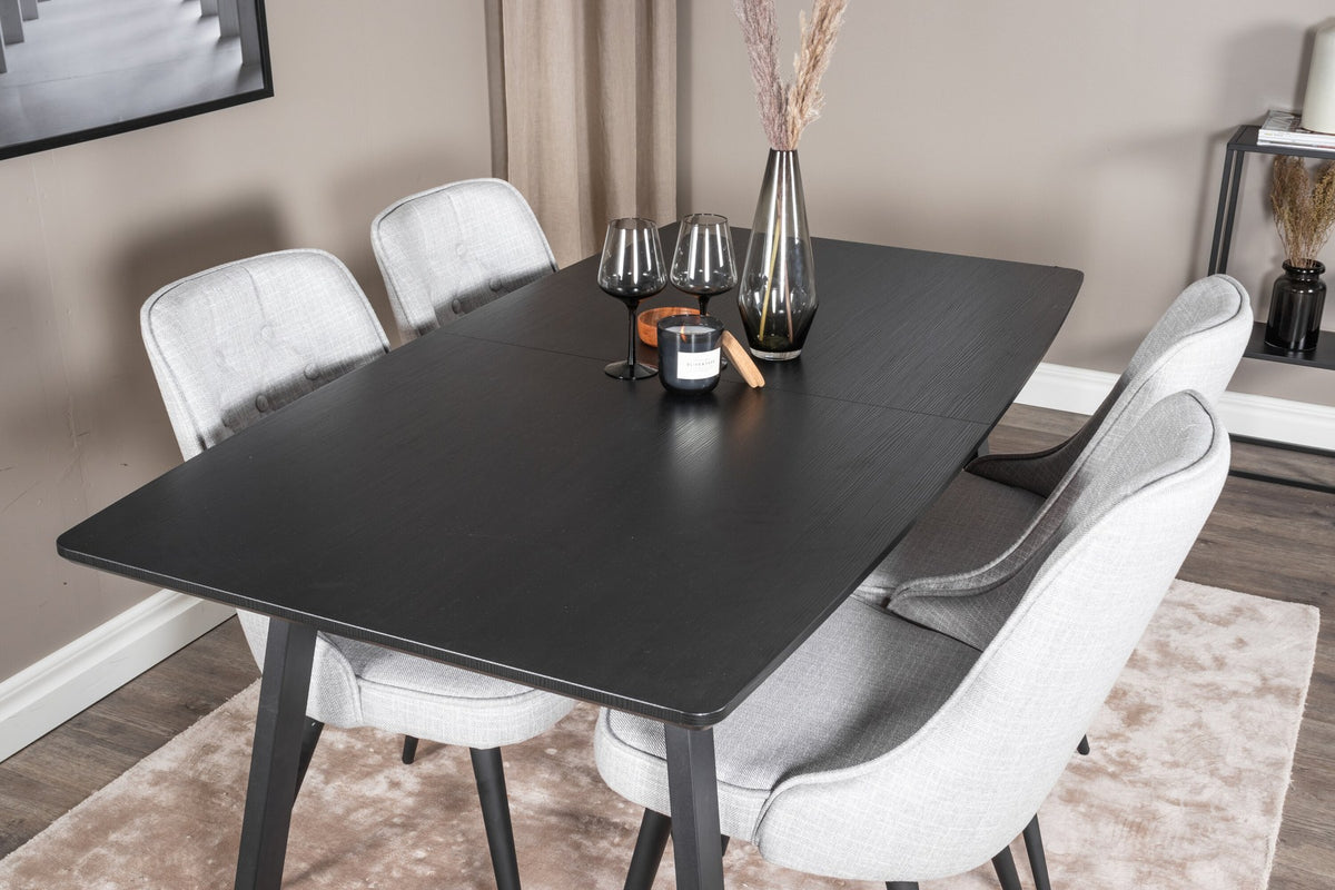 Rechteckiger Esstisch Inca in Schwarz mit ausziehbarer MDF-Platte und Stahlbeinen, daneben zwei gepolsterte Velvet-Esszimmerstühle in Grau von Venture Home.