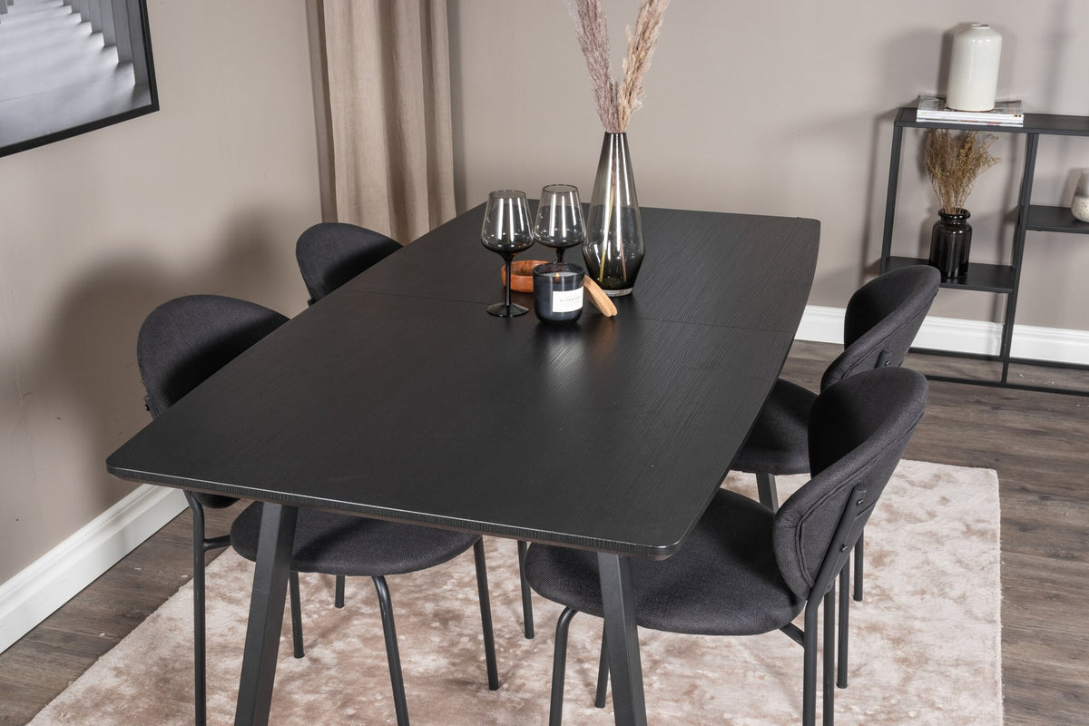 Zwei schwarze Esszimmerstühle aus MDF und Stahl neben einem rechteckigen Esstisch mit schwarzer Tischplatte und Stahlbeinen.