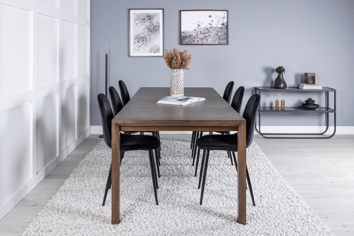 Rechteckiger Esstisch aus Eiche in Natur mit ausziehbarer Platte, dazu zwei schwarze Esszimmerstühle mit gepolsterter Sitzfläche von Venture Home.