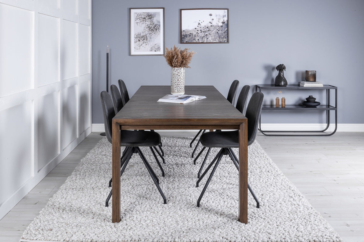 Rechteckiger Esstisch aus Eiche in Natur mit ausziehbarer Platte, dazu zwei schwarze Esszimmerstühle mit gepolsterter Sitzfläche von Venture Home.