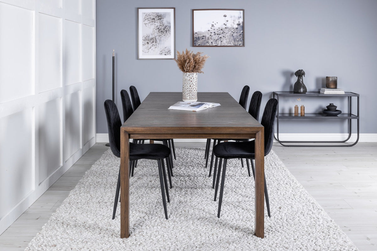 Rechteckiger Esstisch aus Eiche in Natur mit ausziehbarer Platte, dazu zwei schwarze Esszimmerstühle mit gepolsterter Sitzfläche von Venture Home.