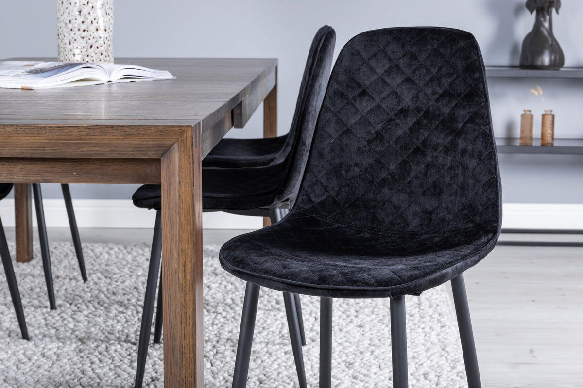 Rechteckiger Esstisch aus Eiche in Natur mit ausziehbarer Platte, dazu zwei schwarze Esszimmerstühle mit gepolsterter Sitzfläche von Venture Home.