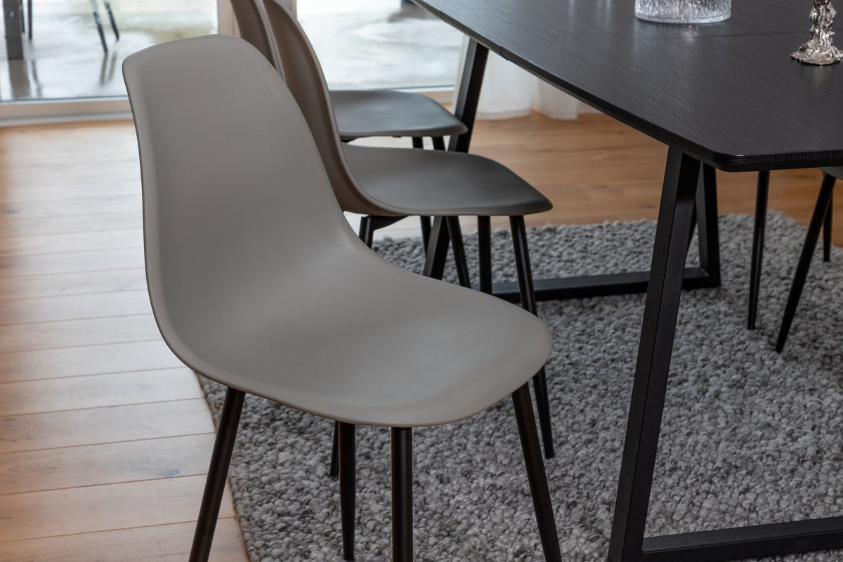 Grauer Esstisch mit schwarzer Tischplatte aus MDF und Stahl, dazu vier Esszimmerstühle mit schwarz pulverbeschichtetem Gestell.