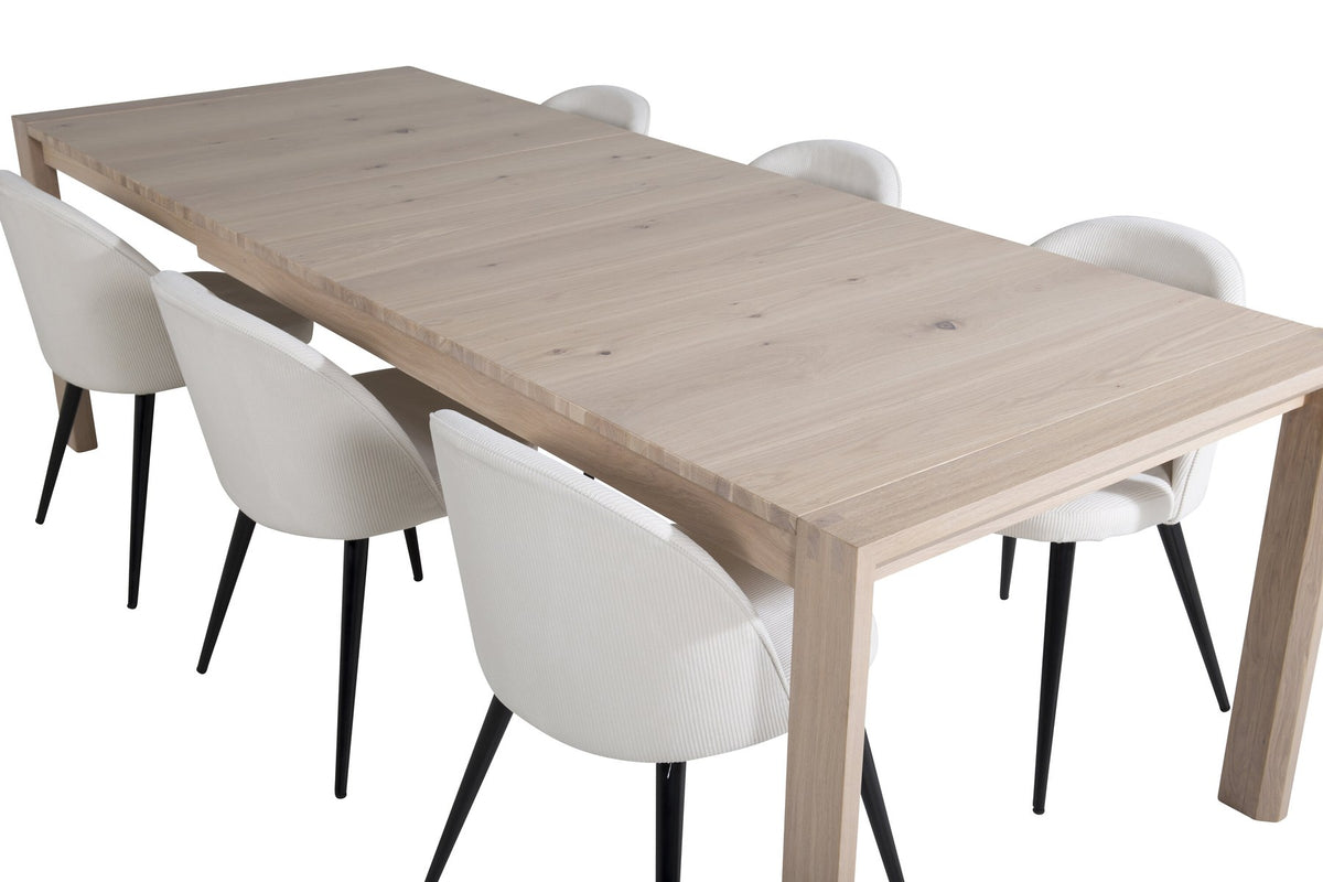 Esstisch mit heller Holzplatte in Naturfarbton auf Eichen-Gestell, umgeben von cremefarbenen Polsterstühlen aus Samt der Velvet-Serie.