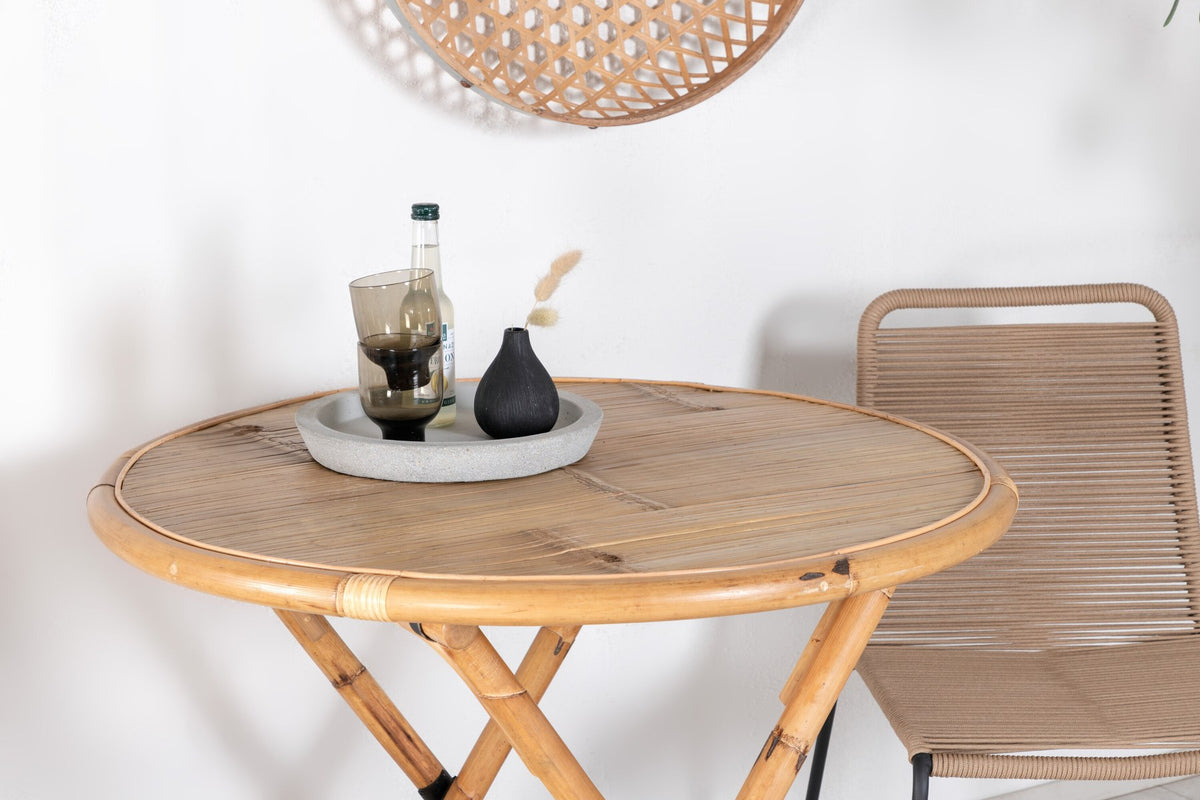Runder Cafétisch aus Bambus mit Stahlbeinen in Natur, daneben zwei stapelbare Stühle aus Bambus und Rattan in Braun, Gartentischset.